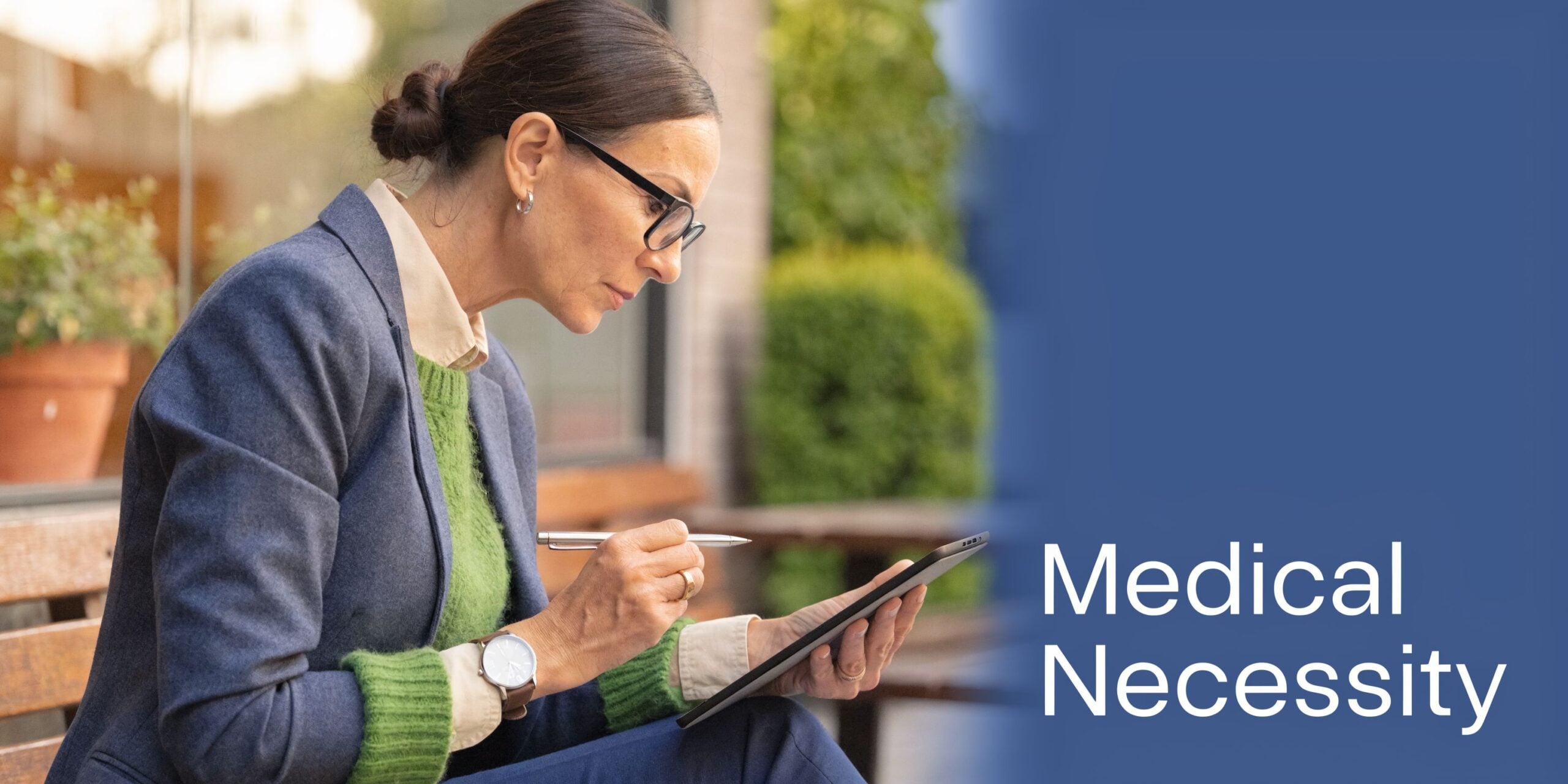 A professional woman reviewing health insurance documentation on a digital tablet while sitting on a bench.