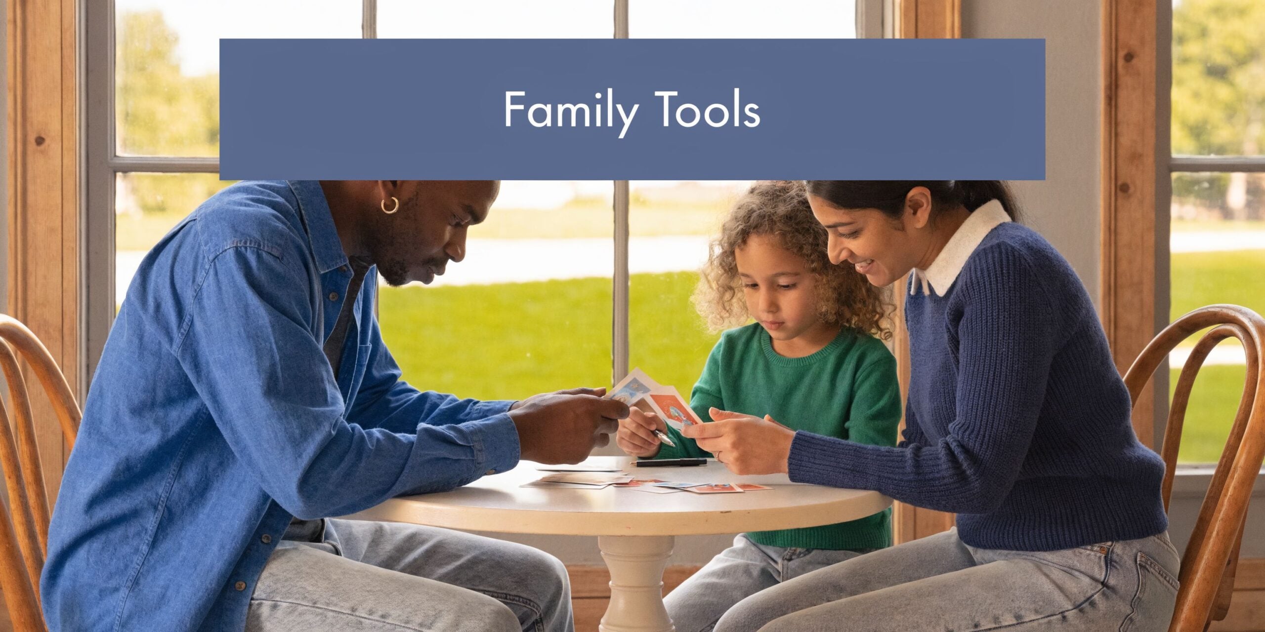 A family of three sitting at a small table engaging in a creative narrative therapy activity together.