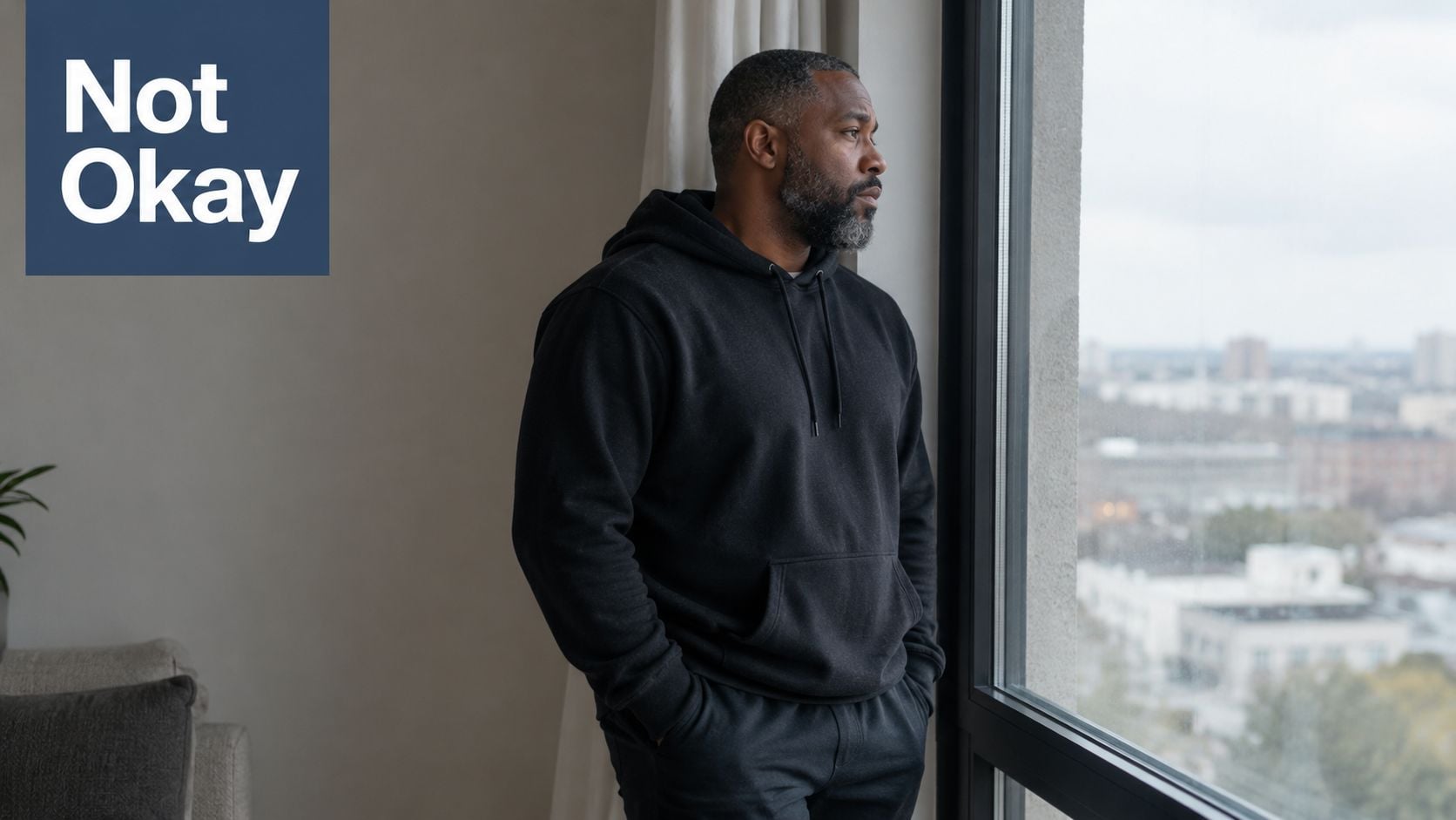 A contemplative man with a graying beard looking out a window, reflecting on his personal recovery journey.